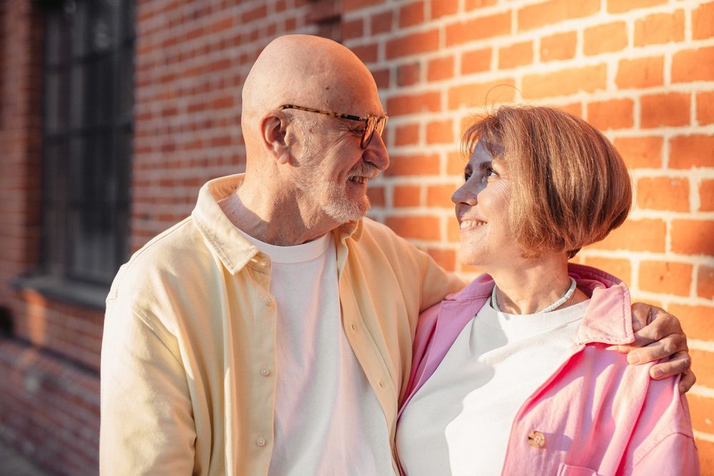 An older couple standing together outside a brick building